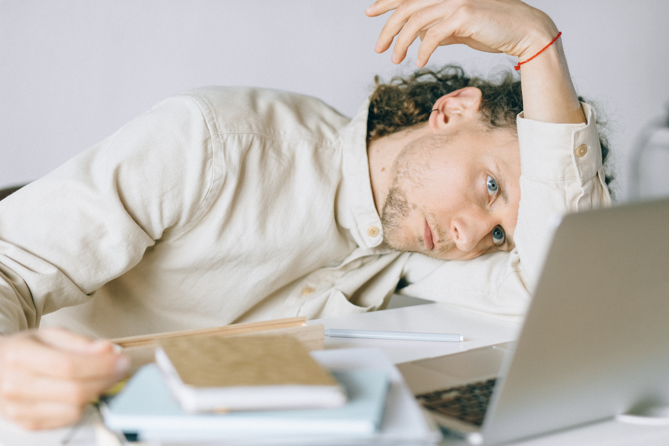 Overworked employee lying in front of laptop, appearing exhausted and needs to overcome burnout.