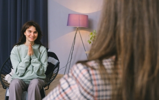 Happy young woman and psychologist discussing positive psychology in modern office
